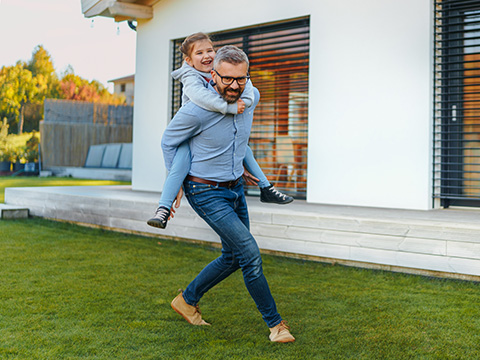 Father with his little daughter having fun in their backyard during sunny autumn day.